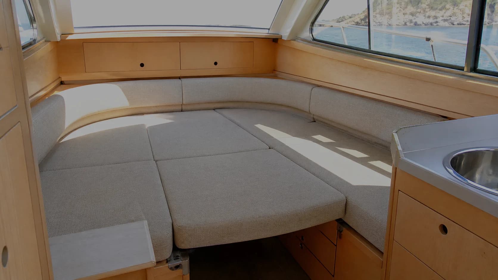 Quadrato di un cabinato con il tavolo abbassato e i cuscini disposti a formare un letto