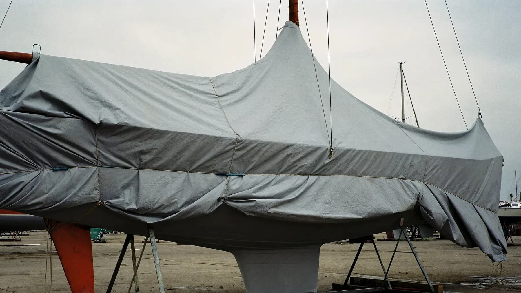 Barca a vela avvolta in un telo invernale su cavalletti in un piazzale